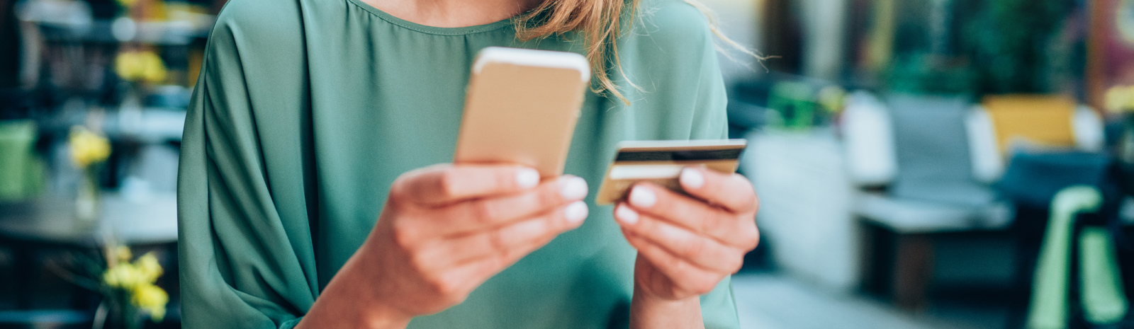 woman holding phone and debit/credit card